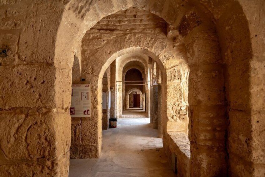 An arched stone corridor with a signboard. 2