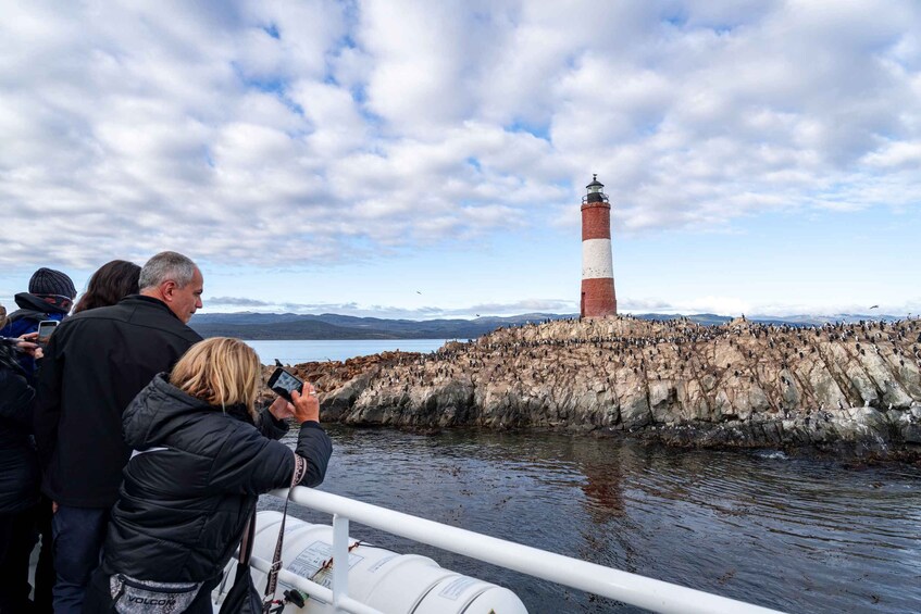 A lighthouse on a rocky outcrop with people taking photos. 1