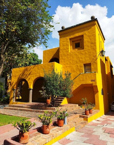 A yellow building with arches and potted plants. 1