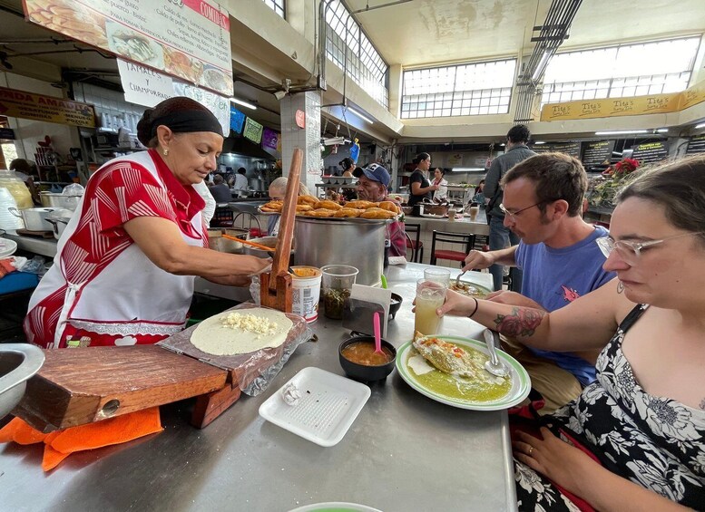 A bustling food stall with a cook preparing food and customers eating. 3