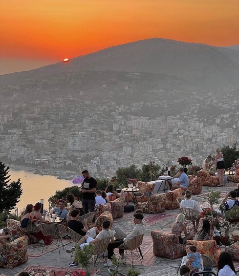 A sunset view over a city with people relaxing on outdoor furniture. 3