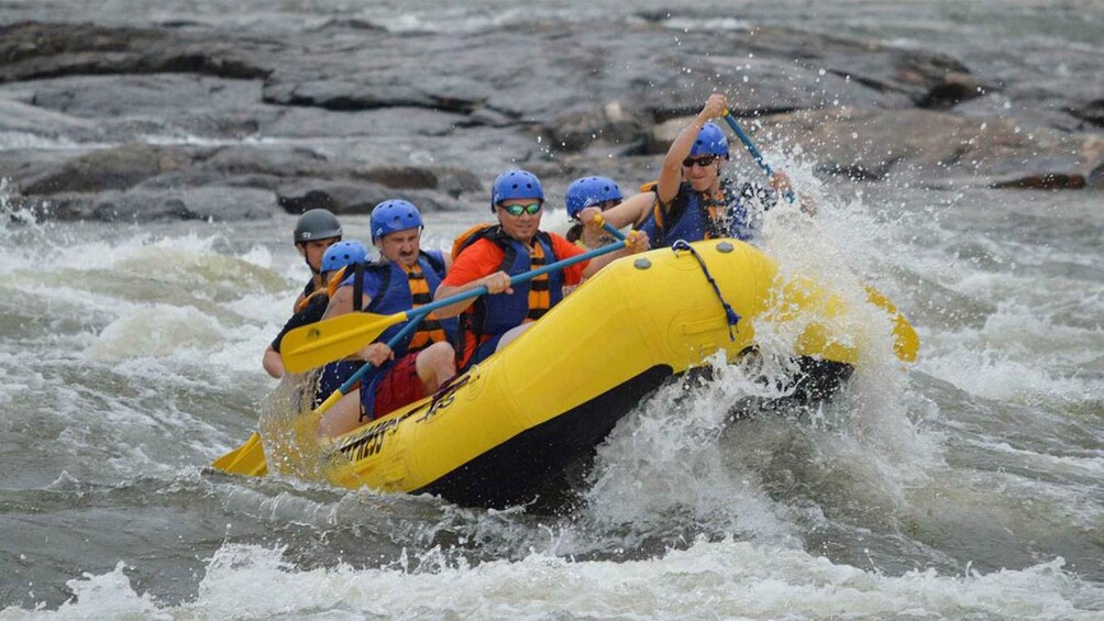 A group of people in a yellow raft navigating through rough waters. 3