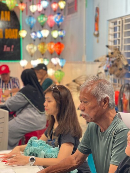 A group of people sitting at a table with a colorful lantern display in the background. 3