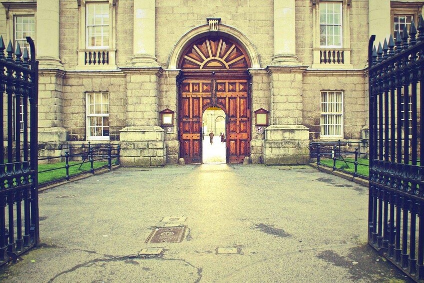 A grand entrance with a large wooden door, flanked by stone walls and black iron gates. 5