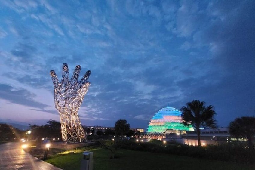 Une grande sculpture de main illuminée et une structure en forme de dôme aux couleurs vives, au crépuscule. 1