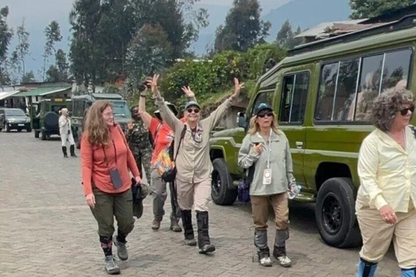 Un groupe de personnes se promène en plein air, certaines portant des vêtements décontractés adaptés à ce type d’activité, et un véhicule vert est garé à proximité. 3