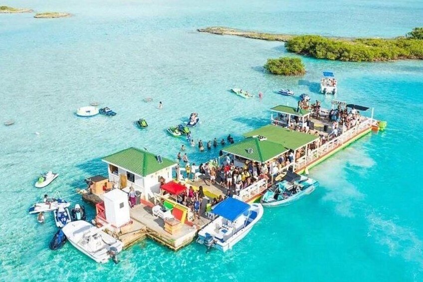 Eine schwimmende Plattform mit Menschen und Booten in türkisblauem Wasser. 4