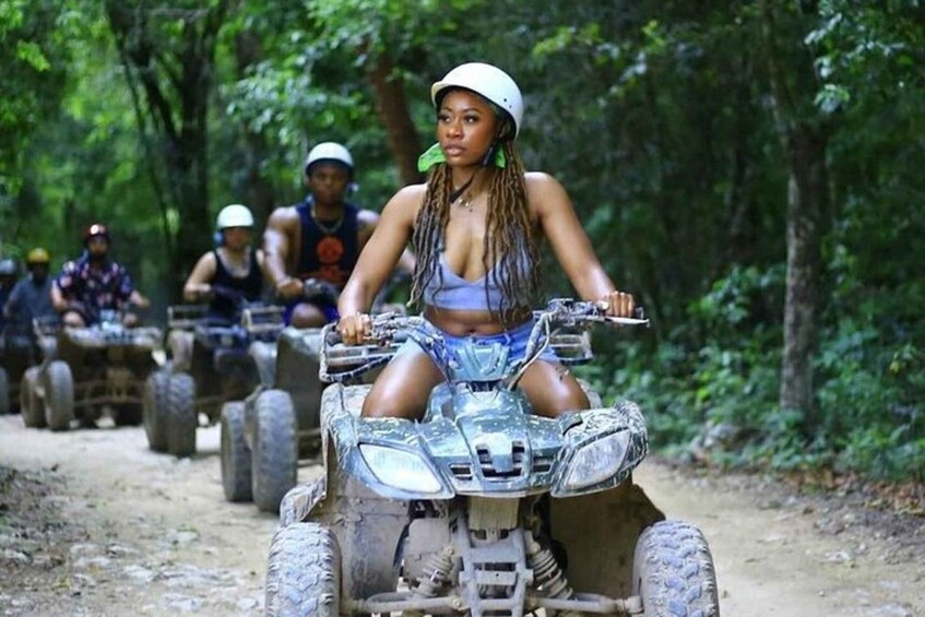 People riding ATVs on a dirt path in a forest. 1