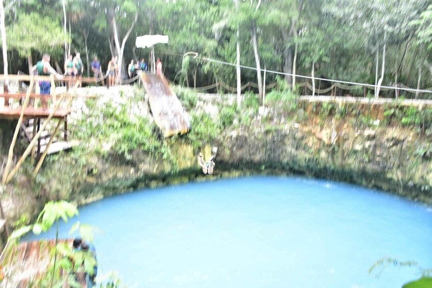 A person bungee jumping from a bridge over a blue body of water surrounded by trees. 2