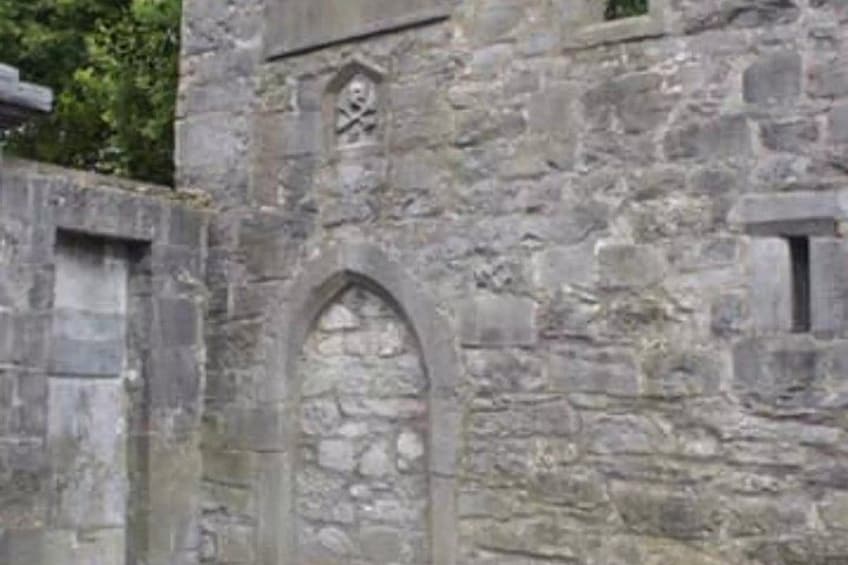 A stone wall with a pointed arch and a small window. 5