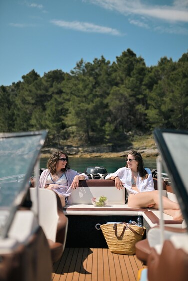 Two people on a boat with a forested shoreline in the background. 1