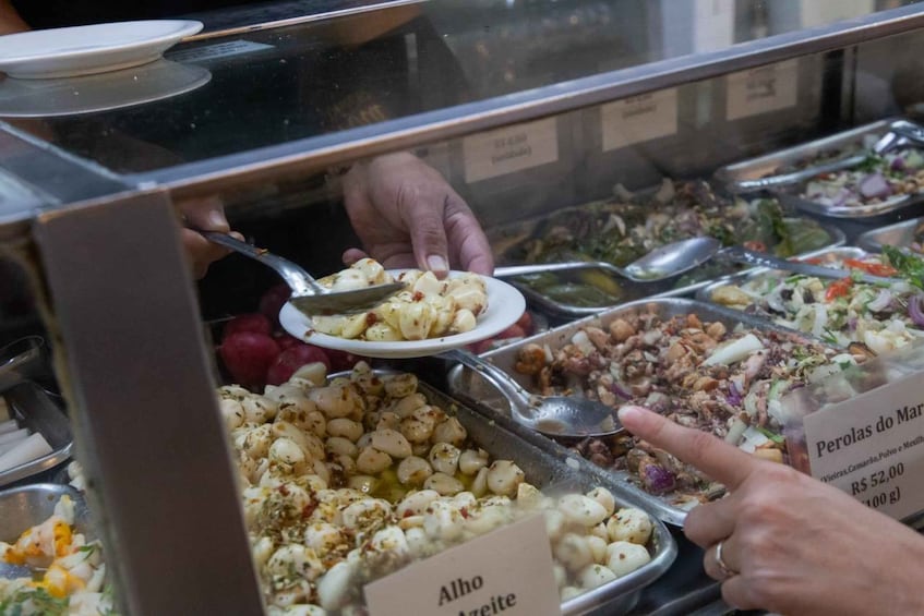 A buffet with various dishes, including a section labeled 'Alho Azeite' and another labeled 'Perolas do Mar.' 1