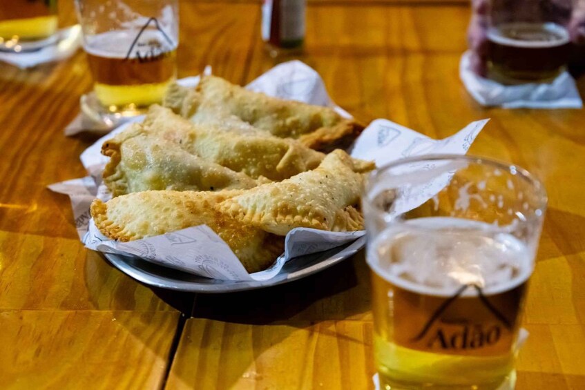 A plate of fried pastries on a wooden table with a glass of beer. 5