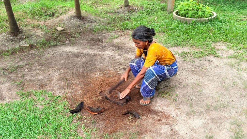 A person crouching on the ground, digging in the soil with a tool. 5