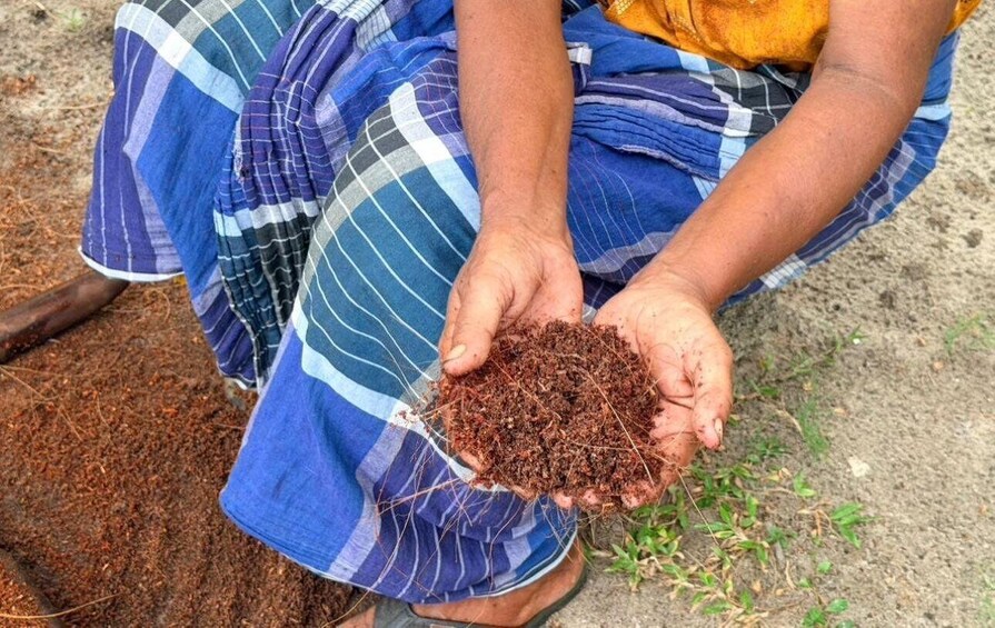 A person holding soil with a blue and white checkered garment. 4