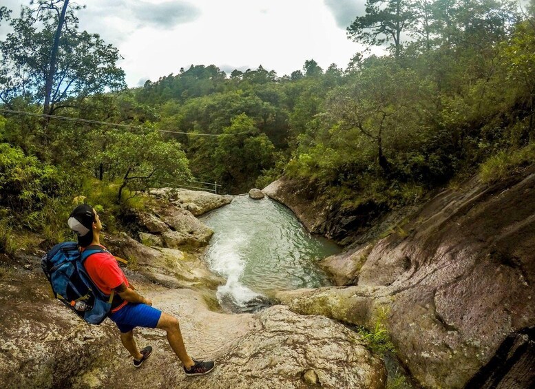 A hiker overlooking a waterfall in a forested area. 2
