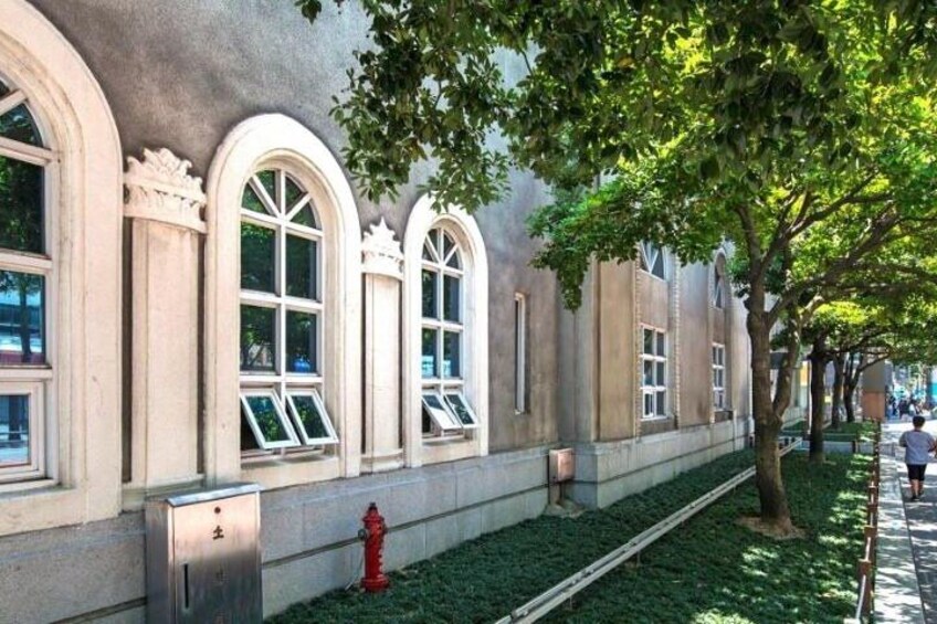 A building with arched windows, a red fire hydrant, and a tree-lined sidewalk. 2