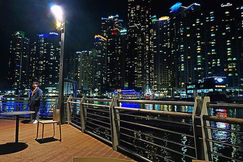 A person sitting on a bench by a waterfront with a city skyline in the background. 4