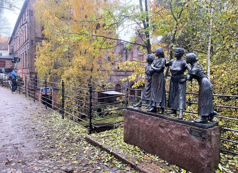 A statue of three figures on a stone pedestal in a park. 4