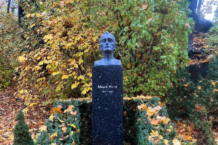 A bust monument with a plaque reading "Edvard Munch 1863-1944" in a park with autumn foliage. 2