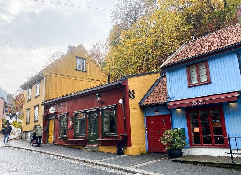 A street with colorful buildings, including a yellow building with a sign 'Natt' and a blue building with a sign 'Chez Colin'. 1