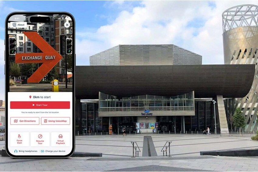 Uno smartphone mostra una mappa, con 'EXCHANGE QUAY' e l'edificio 'The Lowry' sullo sfondo. 1