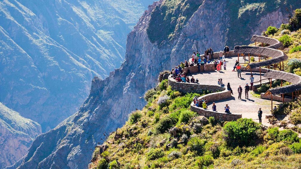 A group of people on a stone viewing platform overlooking a canyon. 1