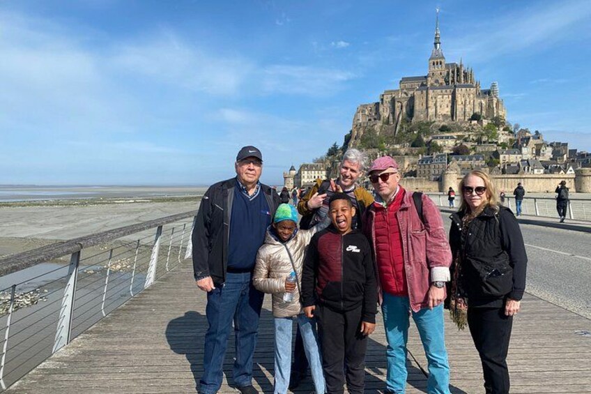 Een groep mensen op een houten looppad, met een historisch kasteel op de achtergrond. 5