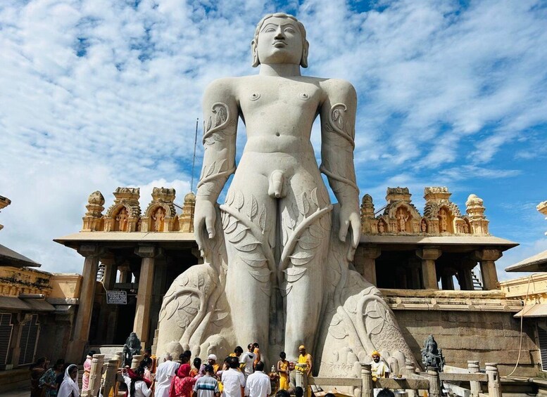 A large stone statue of a figure with intricate carvings, standing in front of a temple with ornate architecture. 5