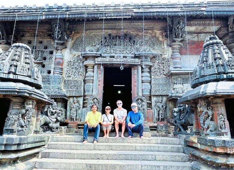 A temple with intricate carvings and three people sitting on the steps. 3