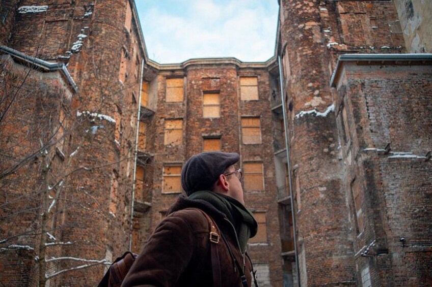 A person standing in a narrow alley between old brick buildings. 1