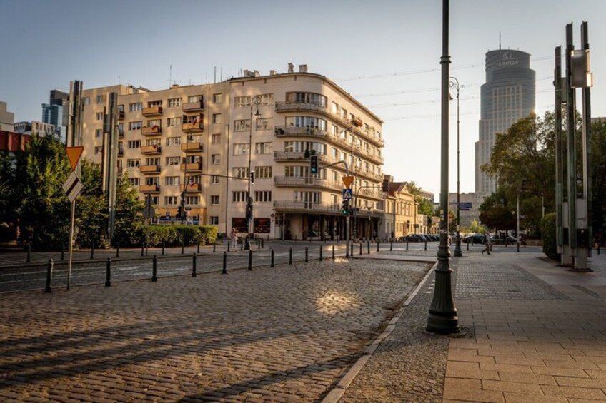 A cobblestone street, a multi-story residential building, and a modern skyscraper in the background. 2