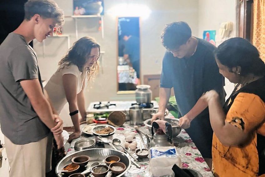 A group of people cooking together in a kitchen with pots, pans, and a table full of food. 4