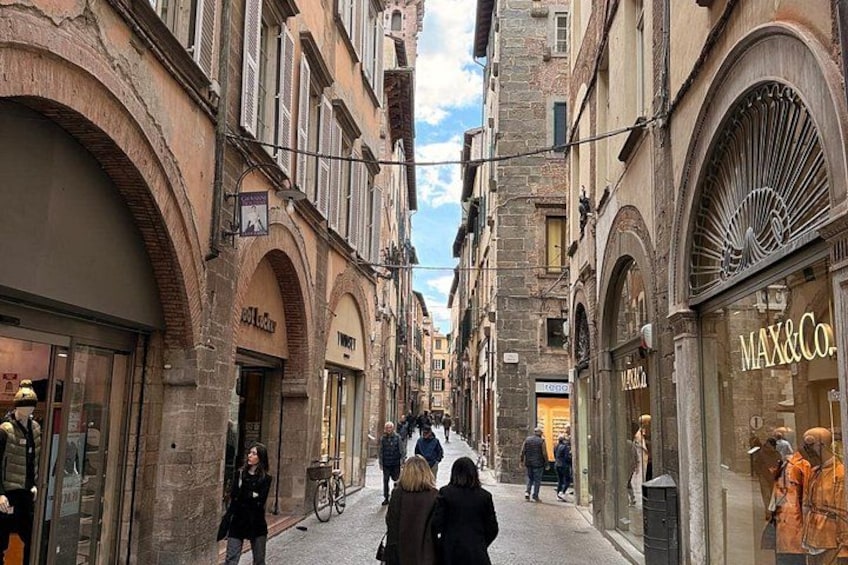 A narrow street lined with historic buildings, a bicycle, and pedestrians. 5