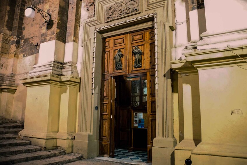 A building entrance with a wooden door, stone steps, and a checkered floor. 3