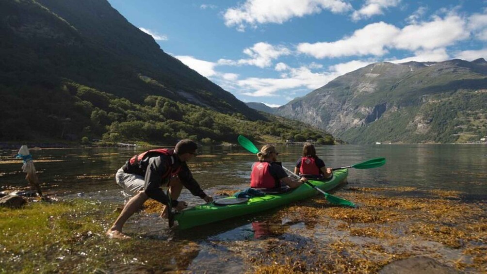 Three people in kayaks on a lake with mountains in the background. 2