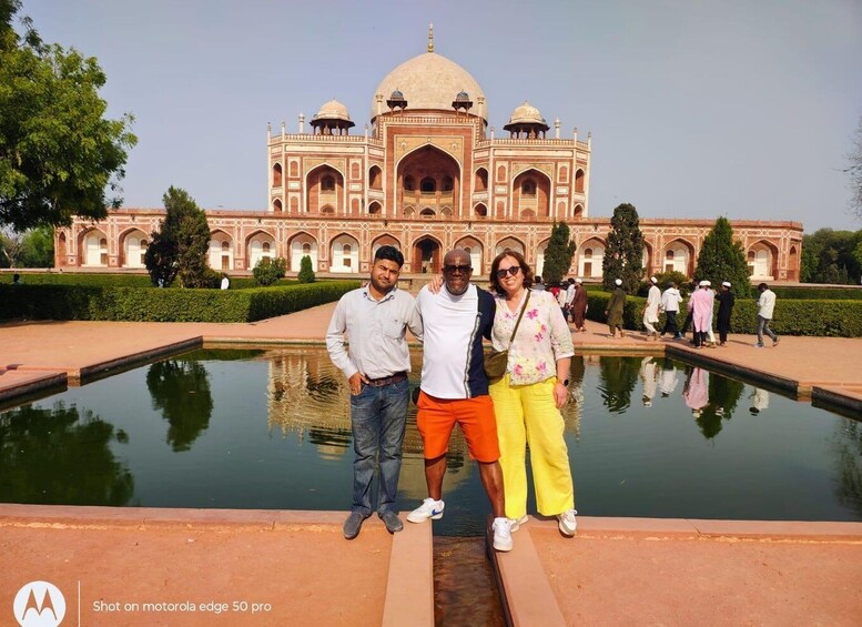 A group of people standing in front of the Taj Mahal with a reflection in the water. 2