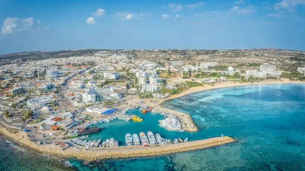 An aerial view of a coastal city with a marina, buildings, and a beach. 3