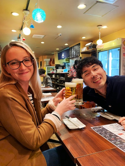 Two people toasting with beer glasses at a restaurant. 5