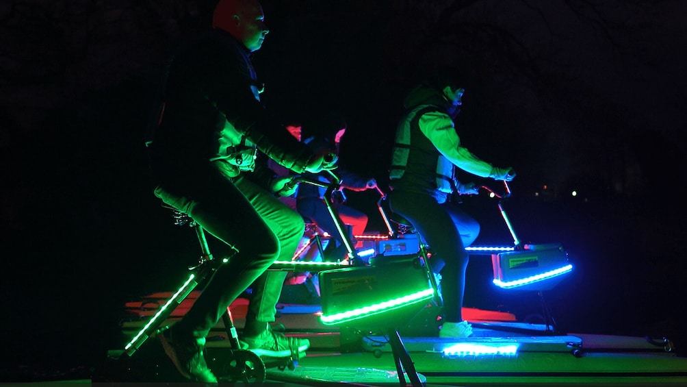 Two people riding illuminated electric bikes at night. 2