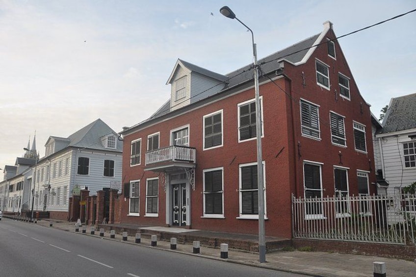 A red brick building with a balcony, white trim, and a white fence. 2
