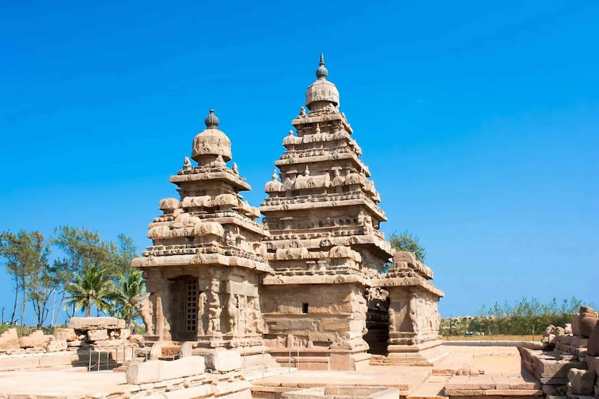 A temple with multiple tiers and intricate carvings, surrounded by palm trees and clear skies. 5