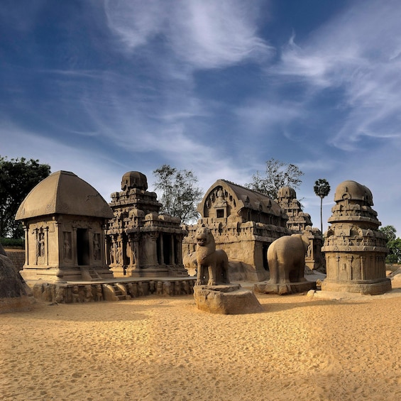 Ancient stone structures with domed roofs and intricate carvings, set in a sandy landscape. 1