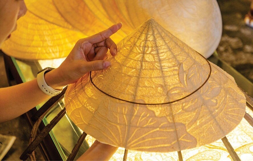 Una persona sostiene un sombrero cónico tradicional con diseños elaborados. 4