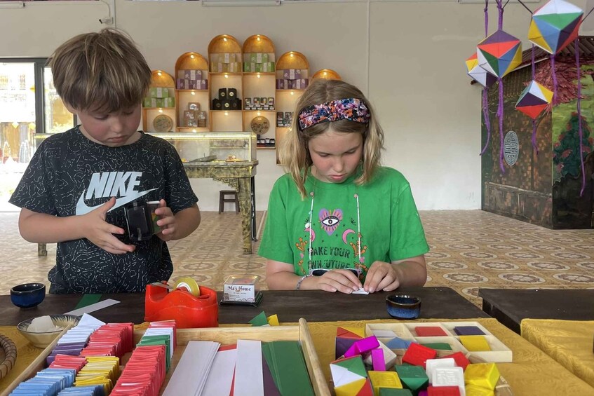 Dos personas en una mesa con materiales de manualidades, como papel de colores y tijeras. 2