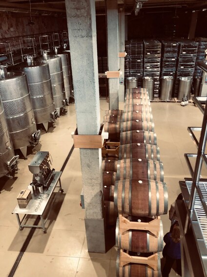 A warehouse with large metal tanks and wooden barrels. 3