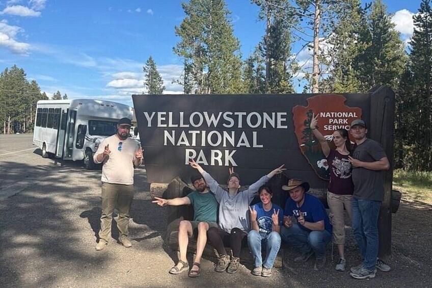 Eine Gruppe von Personen posiert vor einem Schild für den Yellowstone Nationalpark. 4