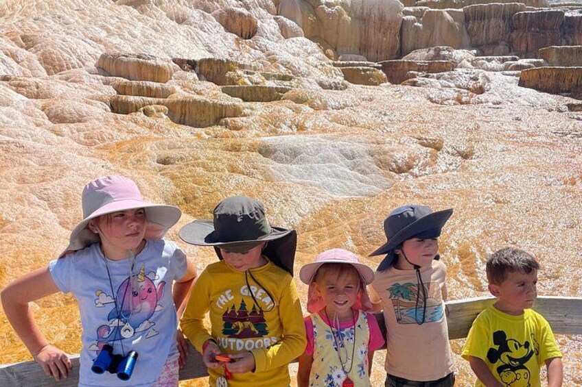 A group of people standing in front of a geological formation with layered rock structures. 4