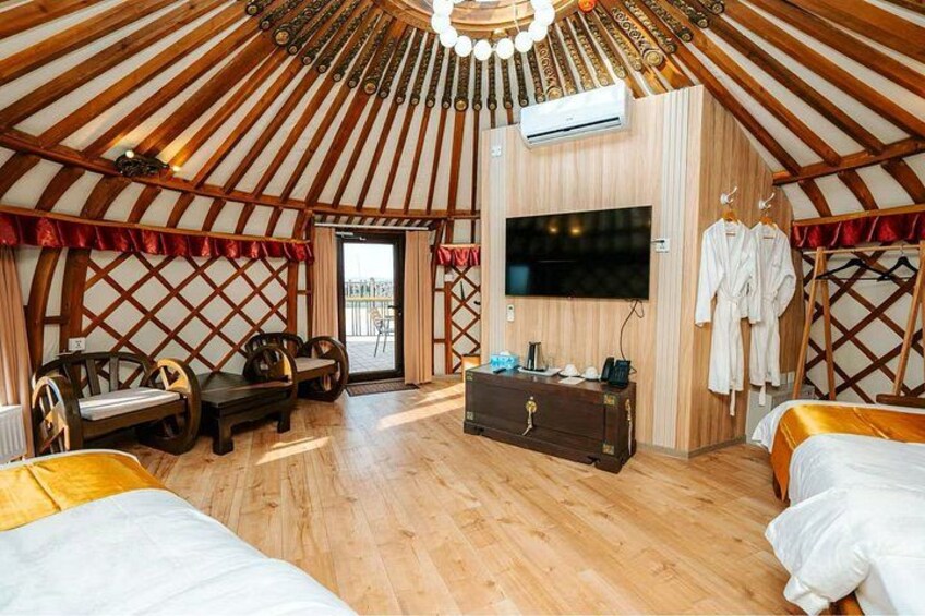 A traditional yurt interior with wooden walls, a sofa, a TV, and a wardrobe. 3