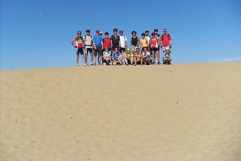 A group of people standing on a sandy hill with a clear blue sky. 4